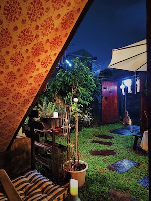 An outdoor seating area with a table and chairs, a potted plant, and a small garden. - Charming Home Chiang Mai (Chiang Mai)