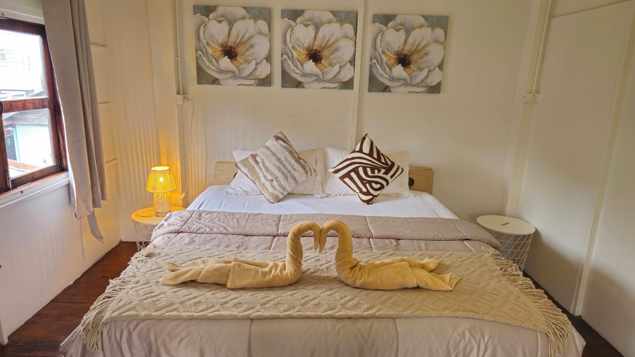 A hotel room with a bed, a lamp, and three wall-mounted flower paintings.