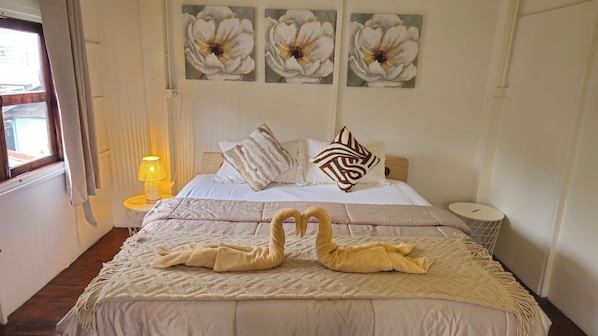 A hotel room with a bed, a lamp, and three wall-mounted flower paintings. - Charming Home Chiang Mai (Chiang Mai)