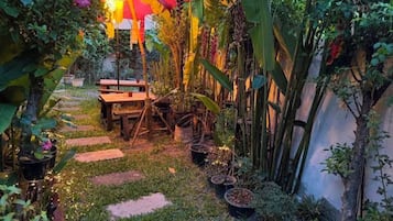 A garden pathway with stepping stones, potted plants, and a wooden bench.