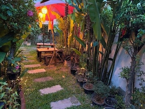 A garden pathway with stepping stones, potted plants, and a wooden bench. - Charming Home Chiang Mai (Chiang Mai)
