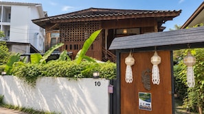 A traditional wooden building with a tiled roof, a white wall with the number 10, and decorative hanging lanterns. - Charming Home Chiang Mai (Chiang Mai)