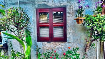 A rustic building with a window, potted plants, and a brick border.