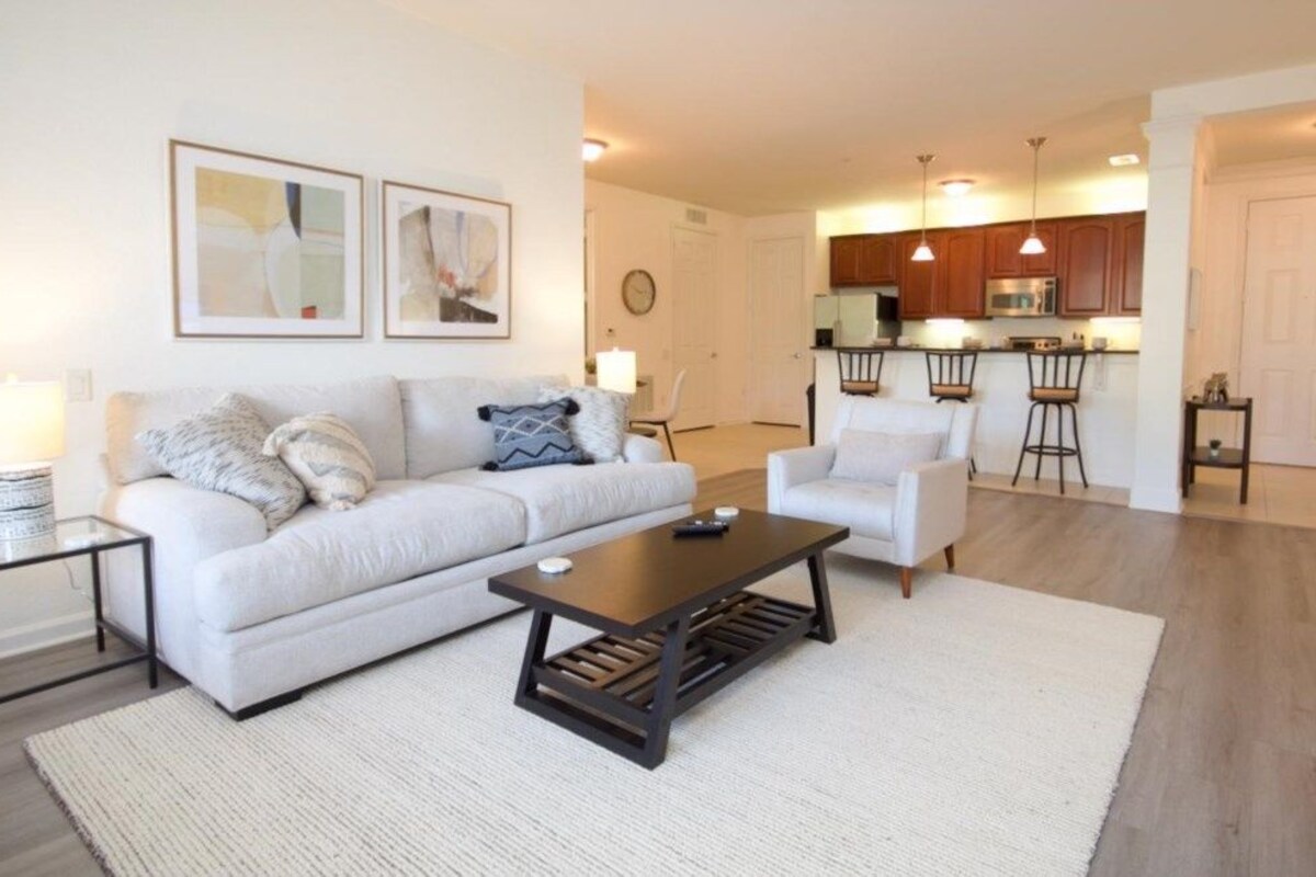 Ein Wohnzimmer mit einer Couch, einem Couchtisch und einer Küchenzeile im Hintergrund.
