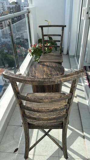 A balcony with a wooden table and chairs, a potted plant, and a view of the cityscape. - Spacious Sea View Apartment  3 Bedrooms  2 Bathrooms (Colombo)
