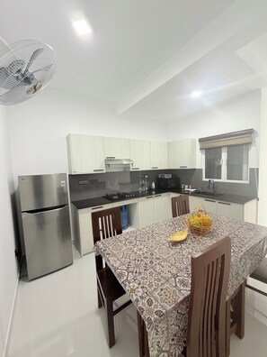 A modern kitchen with white cabinets, a stainless steel refrigerator, a gas stove, and a dining table with chairs. - Spacious Sea View Apartment  3 Bedrooms  2 Bathrooms (Colombo)