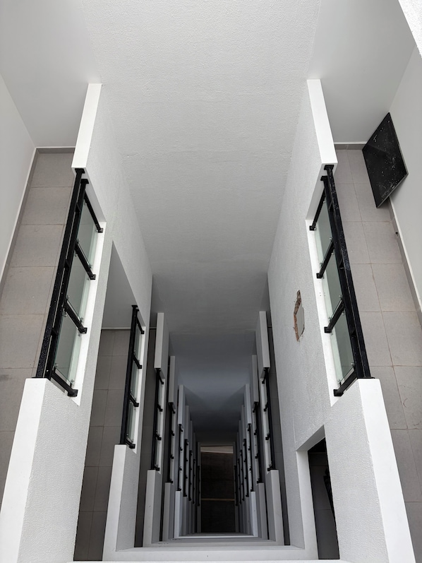 A corridor with a series of windows on both sides, leading to a dark interior.