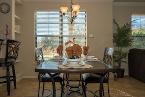 A dining area with a table set for four, chairs, a chandelier, and a window with blinds. - BP914CP 3 Bedroom Condo in Bella Piazza 3 Condo (Davenport)