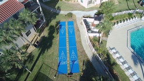 Eine Dachterrasse mit einem blauen Shuffleboard-Spielfeld, einem Swimmingpool und Liegestühlen.