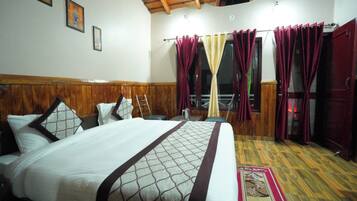 Una habitación de hotel con una cama grande, cabecera de madera, una ventana con cortinas y suelo de madera.