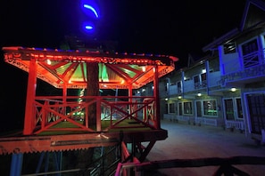 A gazebo with a red frame and green roof, situated in front of a building with multiple windows and a white fence. - Kasar Serenity Resort (Almora)