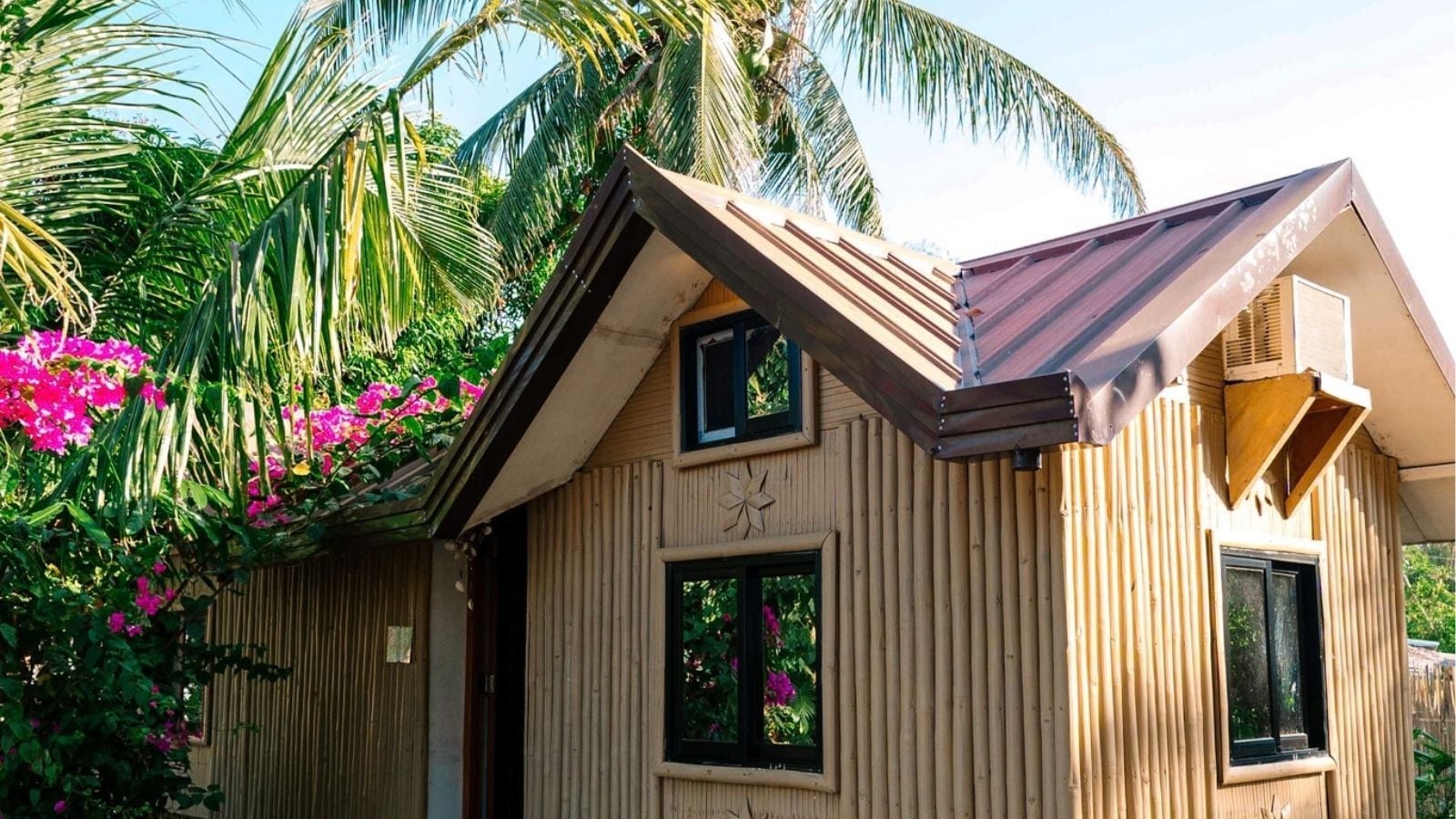 Una casa de madera con techo inclinado, dos ventanas y un adorno de madera sobre la puerta.