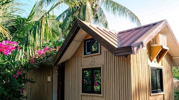 Una casa de madera con techo inclinado, dos ventanas y un adorno de madera sobre la puerta.