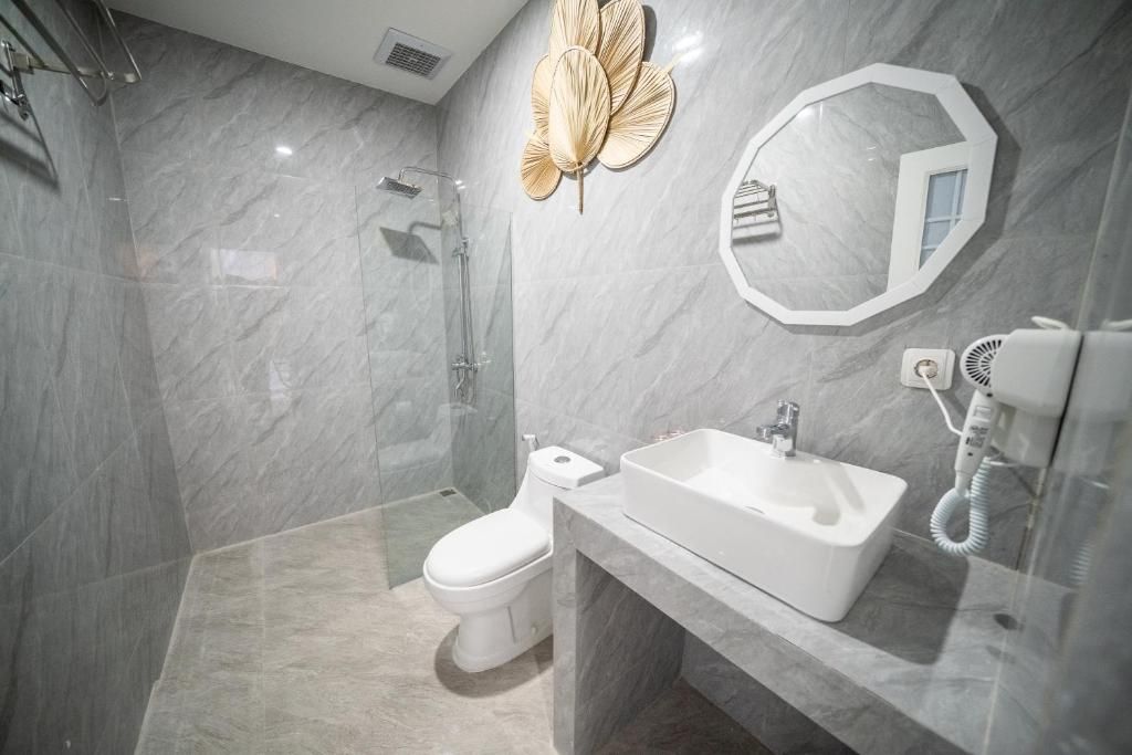 Un baño moderno con cabina de ducha de vidrio, inodoro, lavamanos y secador de pelo.