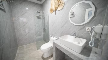 Un baño moderno con cabina de ducha de vidrio, inodoro, lavamanos y secador de pelo.