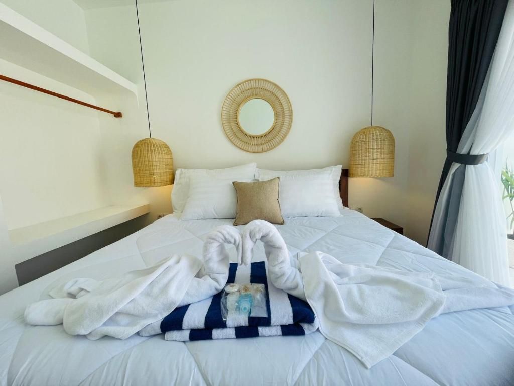 Habitación de hotel con cama, un espejo redondo, dos lámparas de pared y una ventana con cortinas.