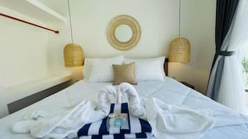 Habitación de hotel con cama, un espejo redondo, dos lámparas de pared y una ventana con cortinas.