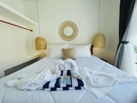 A hotel room with a bed, a round mirror, two wall-mounted lamps, and a window with curtains.