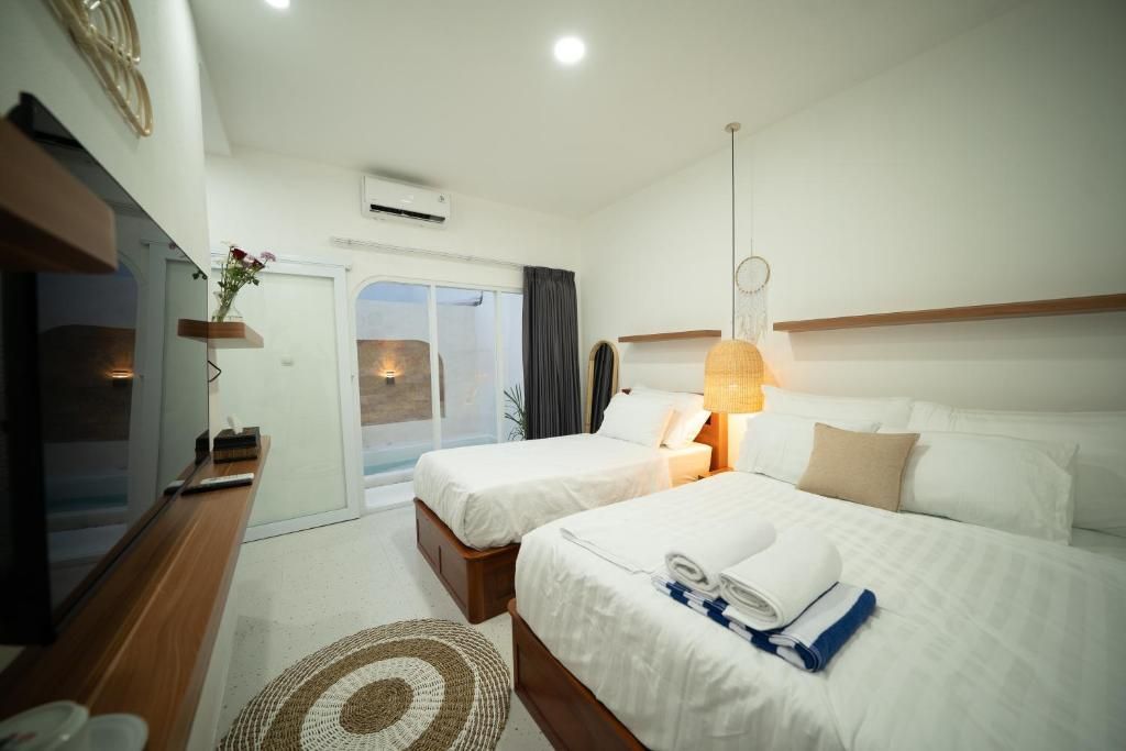 Habitación de hotel con dos camas, televisión, escritorio y vista al exterior.