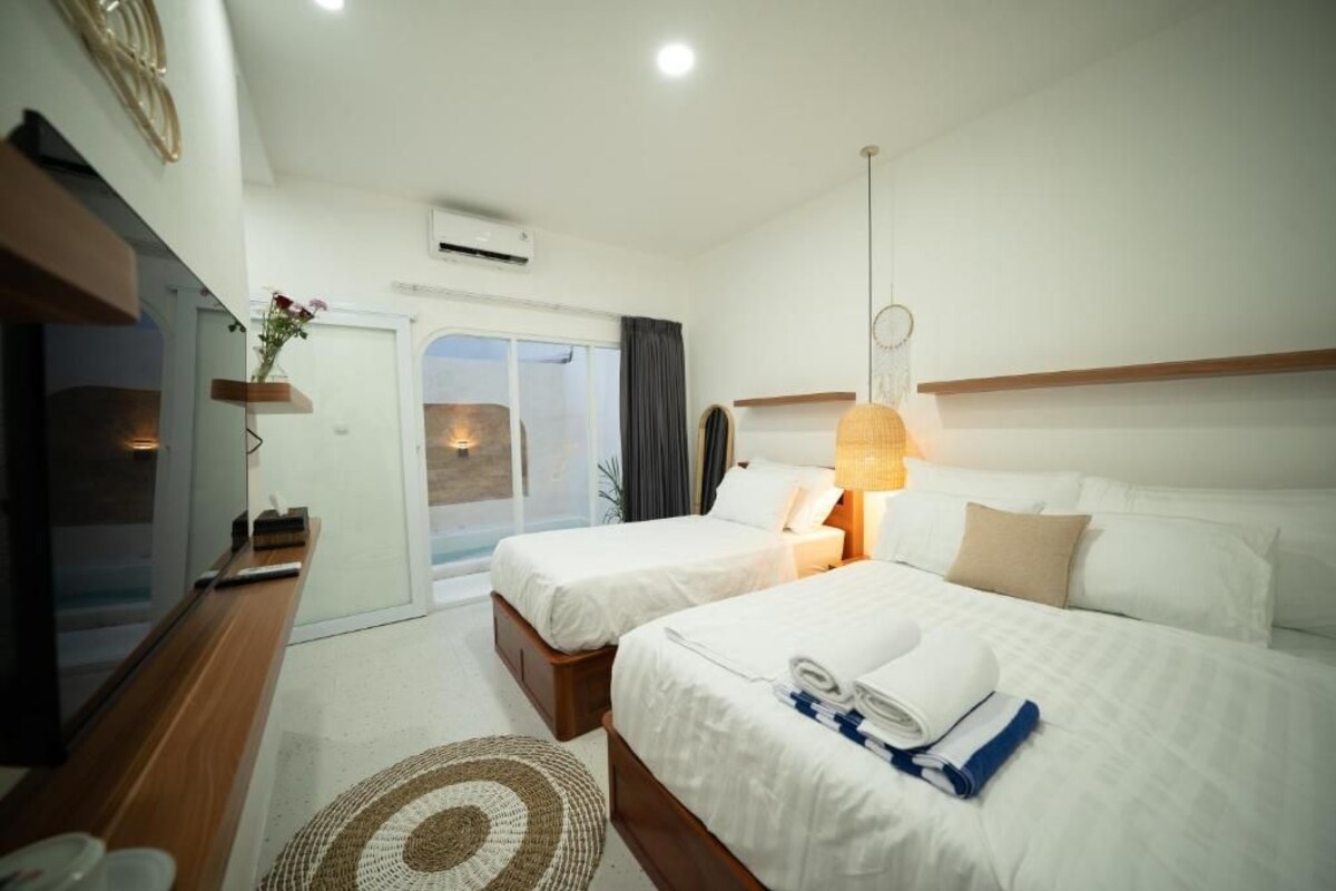 Habitación de hotel con dos camas, televisión, escritorio y vista al exterior.