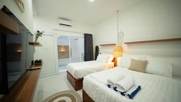 Habitación de hotel con dos camas, televisión, escritorio y vista al exterior.