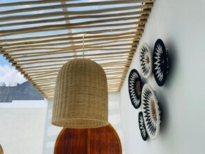Una habitación con ventilador de techo de mimbre, puerta de madera y placas decorativas en la pared.