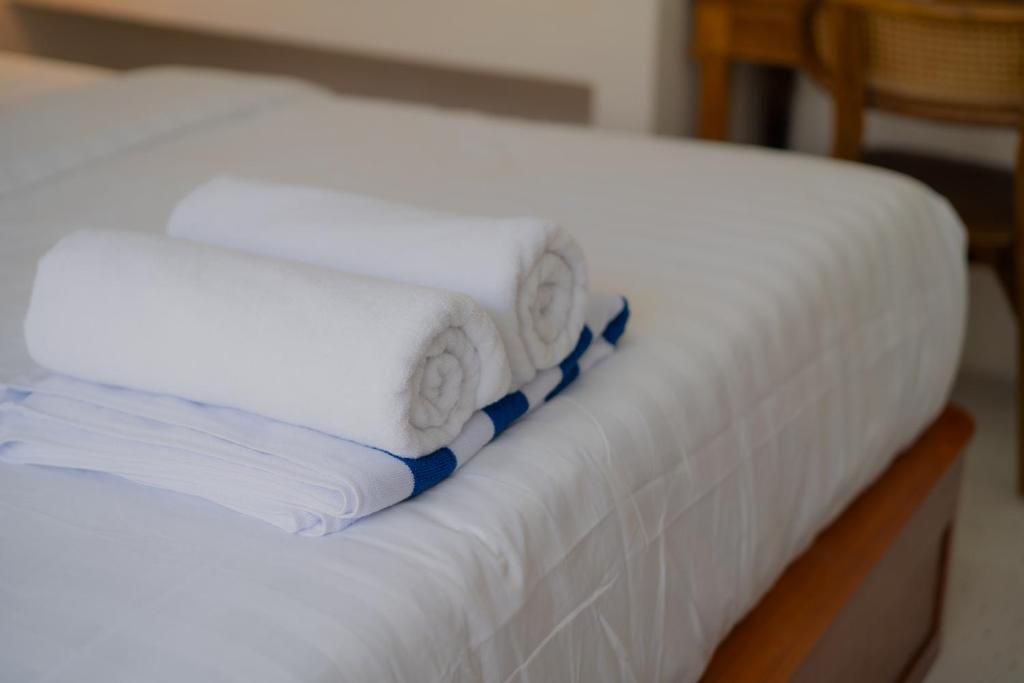 A bed with white bedding and rolled towels.
