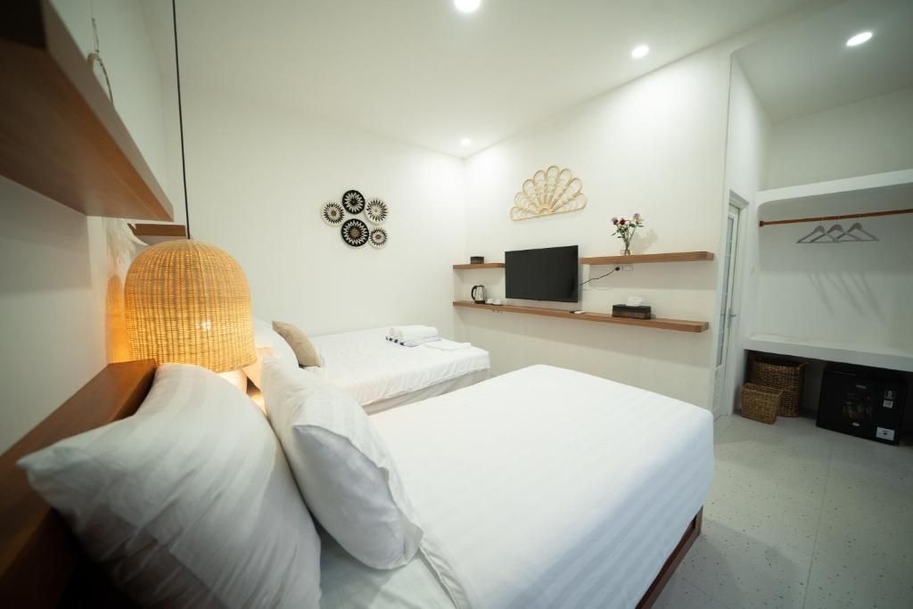 Una habitación de hotel con dos camas, un televisor de pantalla plana, decoración en la pared y una repisa con un florero.