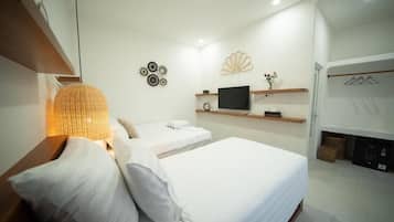 Una habitación de hotel con dos camas, un televisor de pantalla plana, decoración en la pared y una repisa con un florero.