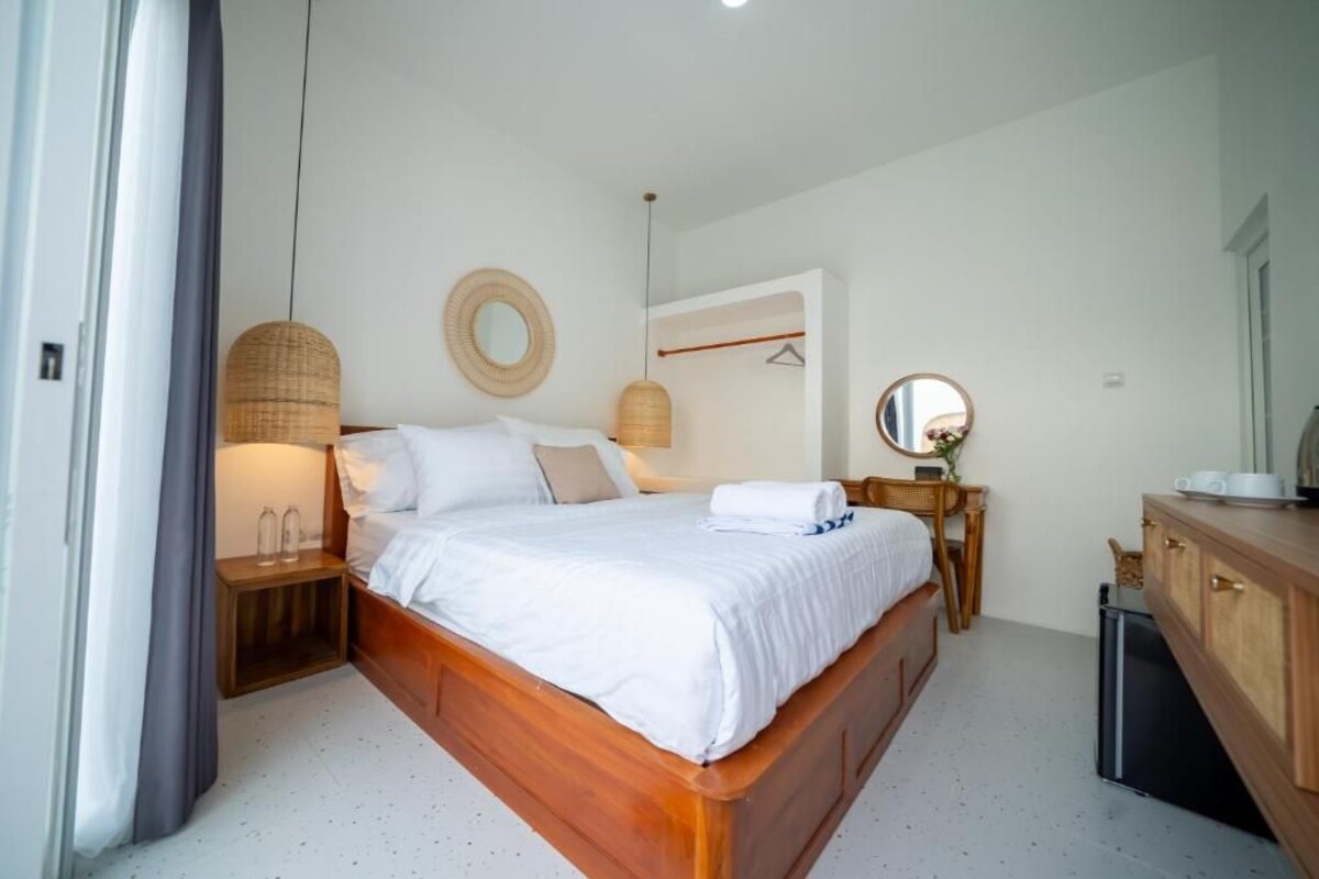 Un dormitorio con una cama de madera, mesitas de noche, un espejo y un armario.