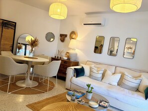 A modern living room with a white sofa, a dining table with chairs, and a coffee table with books and a plant. - A Private Rural Retreat with Two En-suite Casitas (Cómpeta)