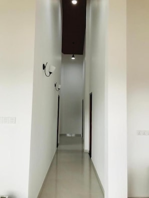 A narrow, well-lit hallway with a light fixture on the left and a door at the end.
