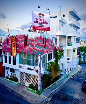 A hotel with a colorful facade, a prominent sign, and a balcony.