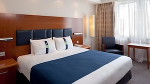 A hotel room with a large bed, a wooden headboard, a desk, a chair, and a lamp. - Holiday Inn Maidenhead - Windsor (Maidenhead)