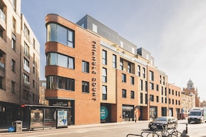 A multi-story building with a prominent 'TRANGLE COURT' sign, a bus stop, and a PUREGYM gym on the ground floor. - Stylish Camberwell Two-Bed Retreat (London)
