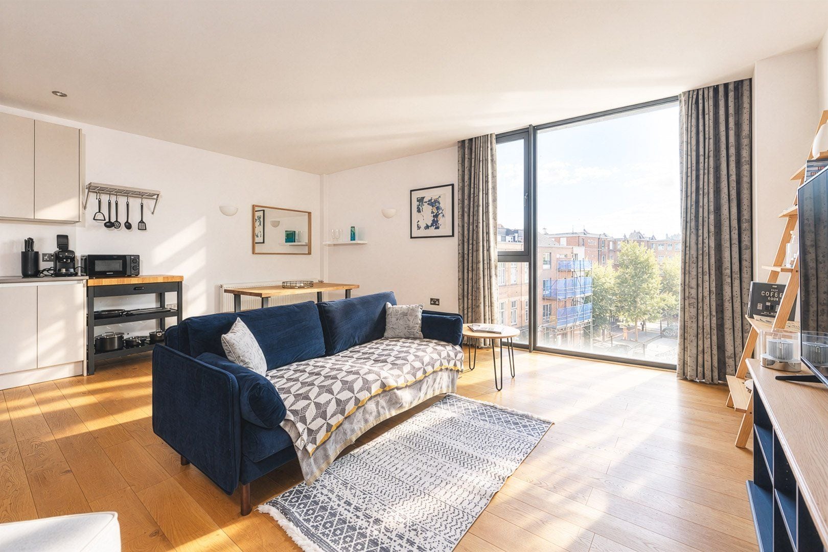 A modern living room with a sofa, a coffee table, a dining table, and a view of the city through large windows.