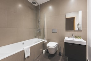 A modern bathroom with a bathtub, toilet, and sink. - Stylish Camberwell Two-Bed Retreat (London)