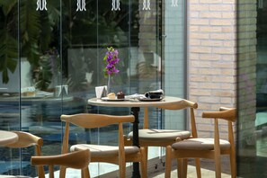 Un cafè amb una taula rodona, dues cadires i un ram de flors morades.