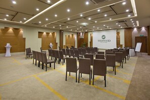 Una sala de conferències amb files de cadires, una pantalla de projector i un senyal de sortida.