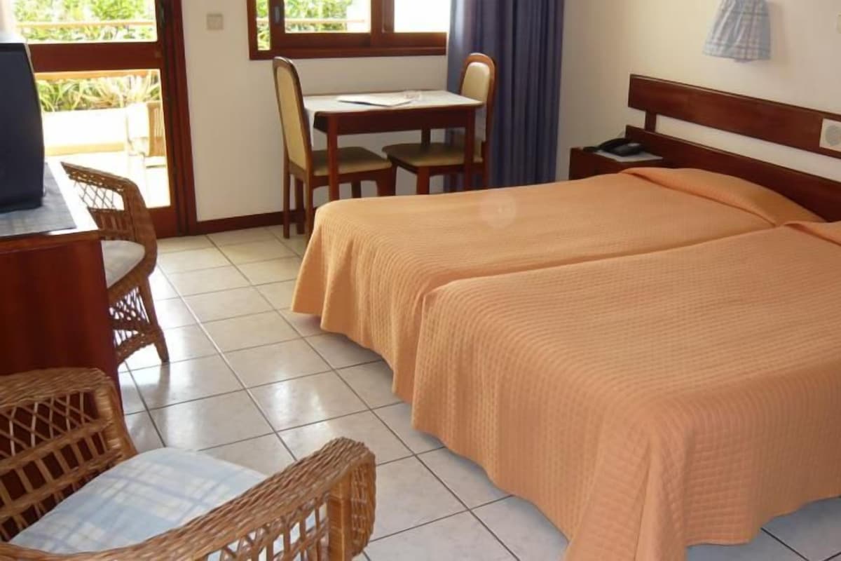 A hotel room with two beds, a desk, and chairs.