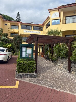 Un hotel con restaurante, bar, jardín, pérgola y un camino de piedra.
