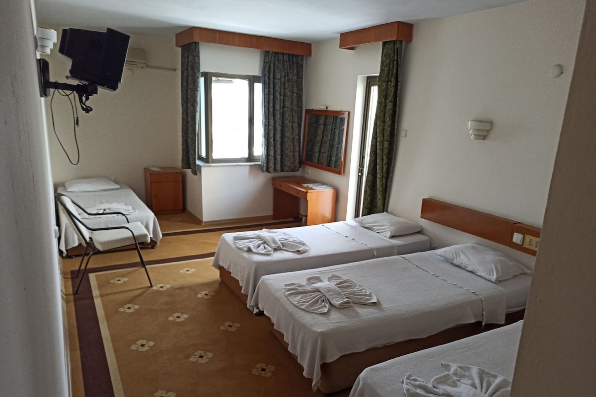 A hotel room with two beds, a desk, a chair, and a television.