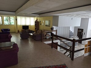 Amplia sala de estar con techo alto, escalera y vistas al exterior.