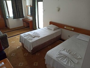 Habitación de hotel con dos camas, una mesita de noche pequeña, un espejo y una ventana con cortinas.