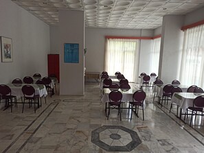 Un salón de conferencias con varias mesas y sillas, un suelo estampado e iluminación empotrada en el techo.