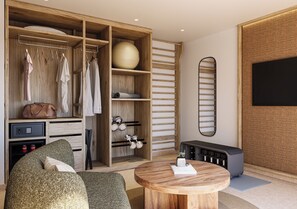A modern room with a wooden wardrobe, a round wooden table, and a television mounted on the wall. - HD Sensarena (Teguise)