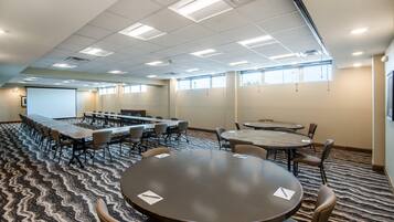 A conference room with a long table and chairs, carpeted floor, and ceiling lights.