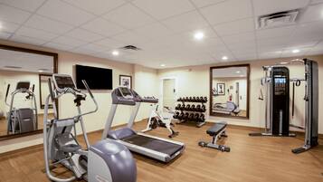 Un gimnasio con cintas de correr, elípticas, pesas libres y máquinas de musculación.