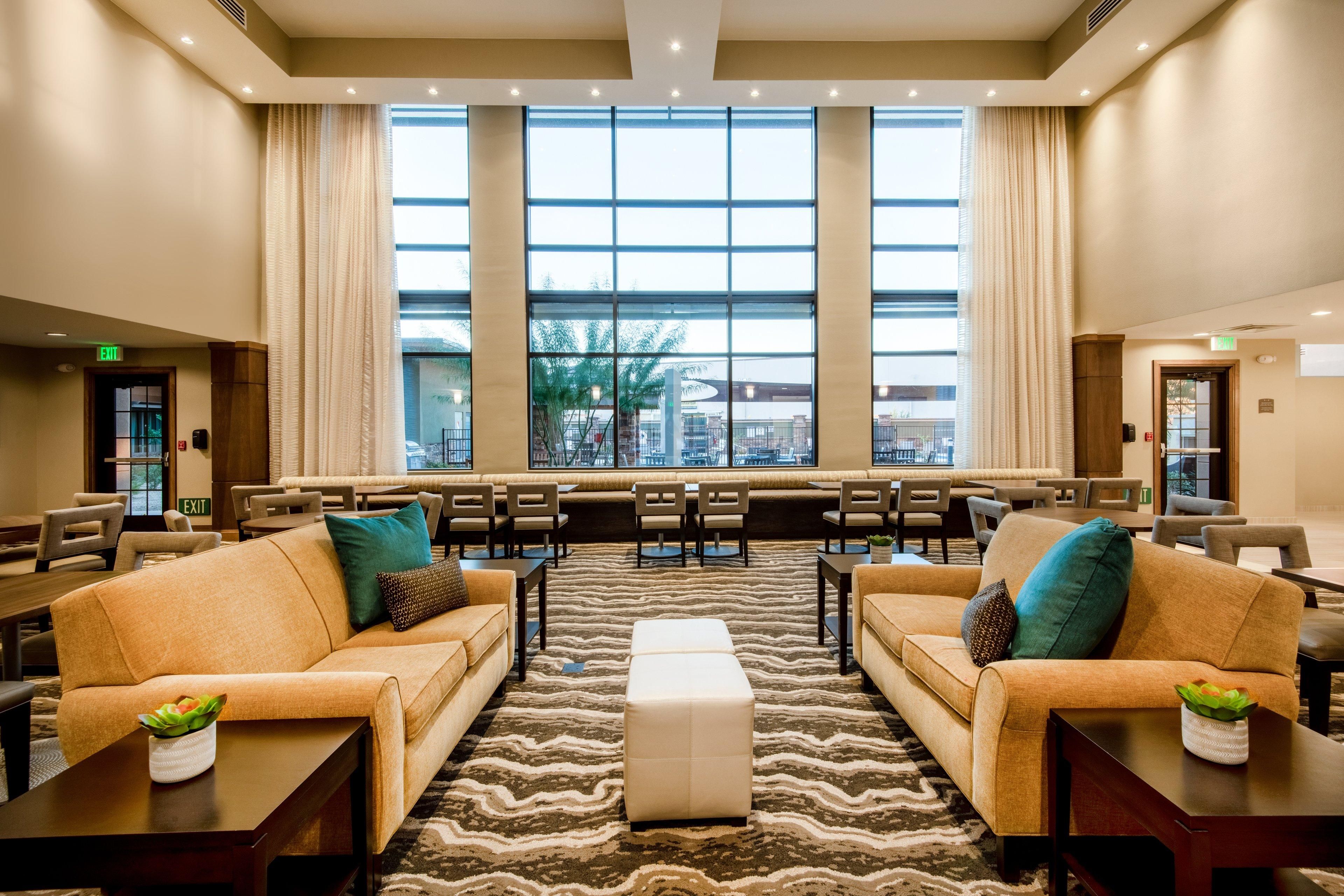A hotel lobby with seating areas, a large window, and an exit sign.