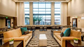 A hotel lobby with seating areas, a large window, and an exit sign.